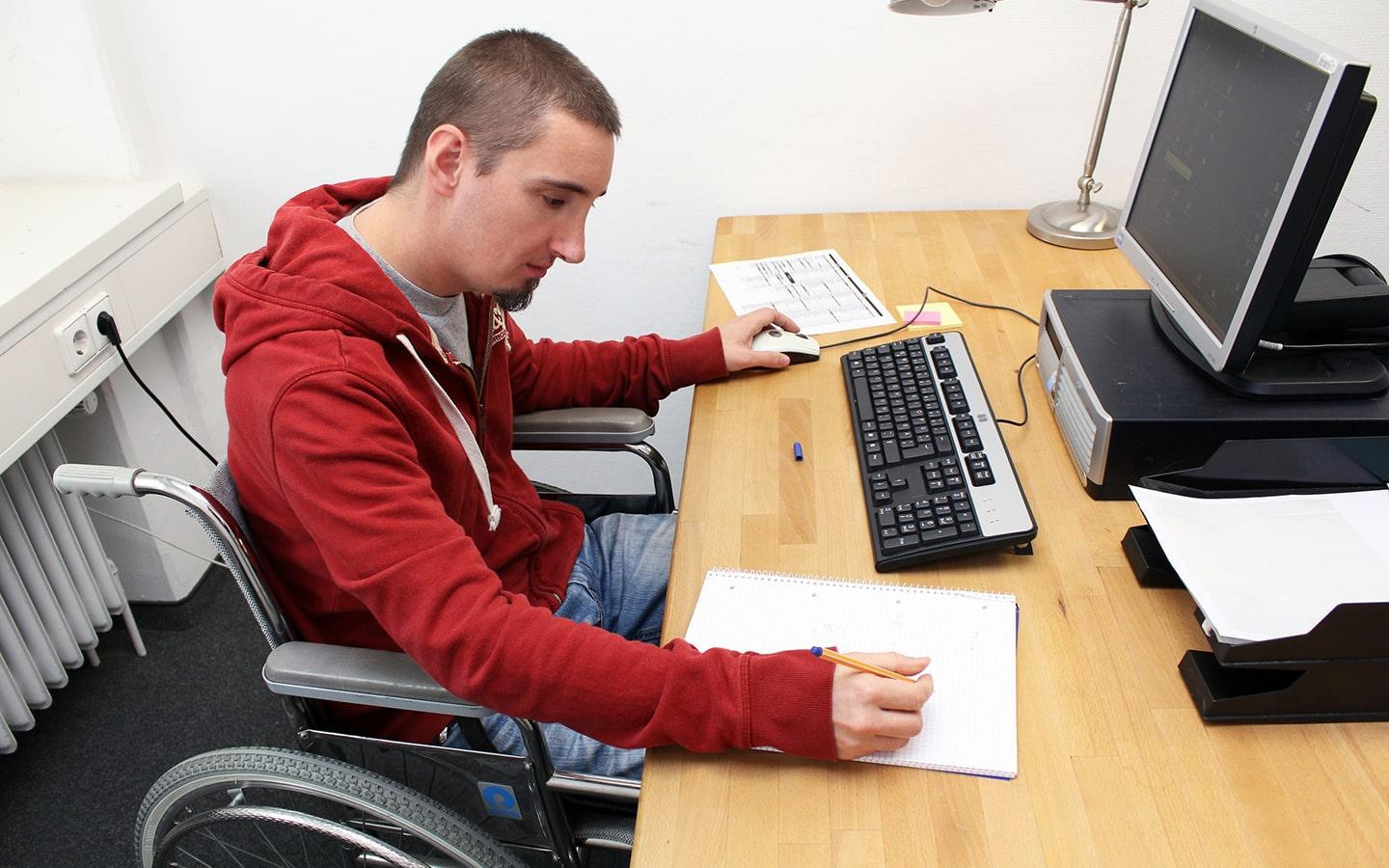 Homme en fauteuil roulant devant un ordinateur